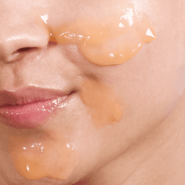 Close-up of a person applying a skincare product to their face.