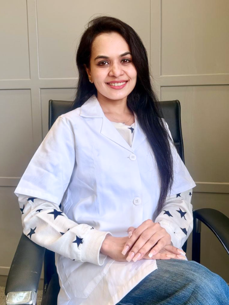 Woman in a white lab coat sitting in a chair against a neutral background