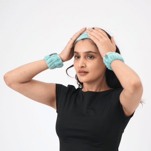 Woman wearing a black top with teal headband and wristbands on a white background