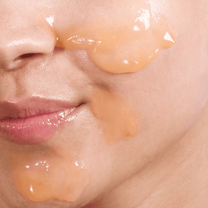 Close-up of a person applying a skincare product to their face.